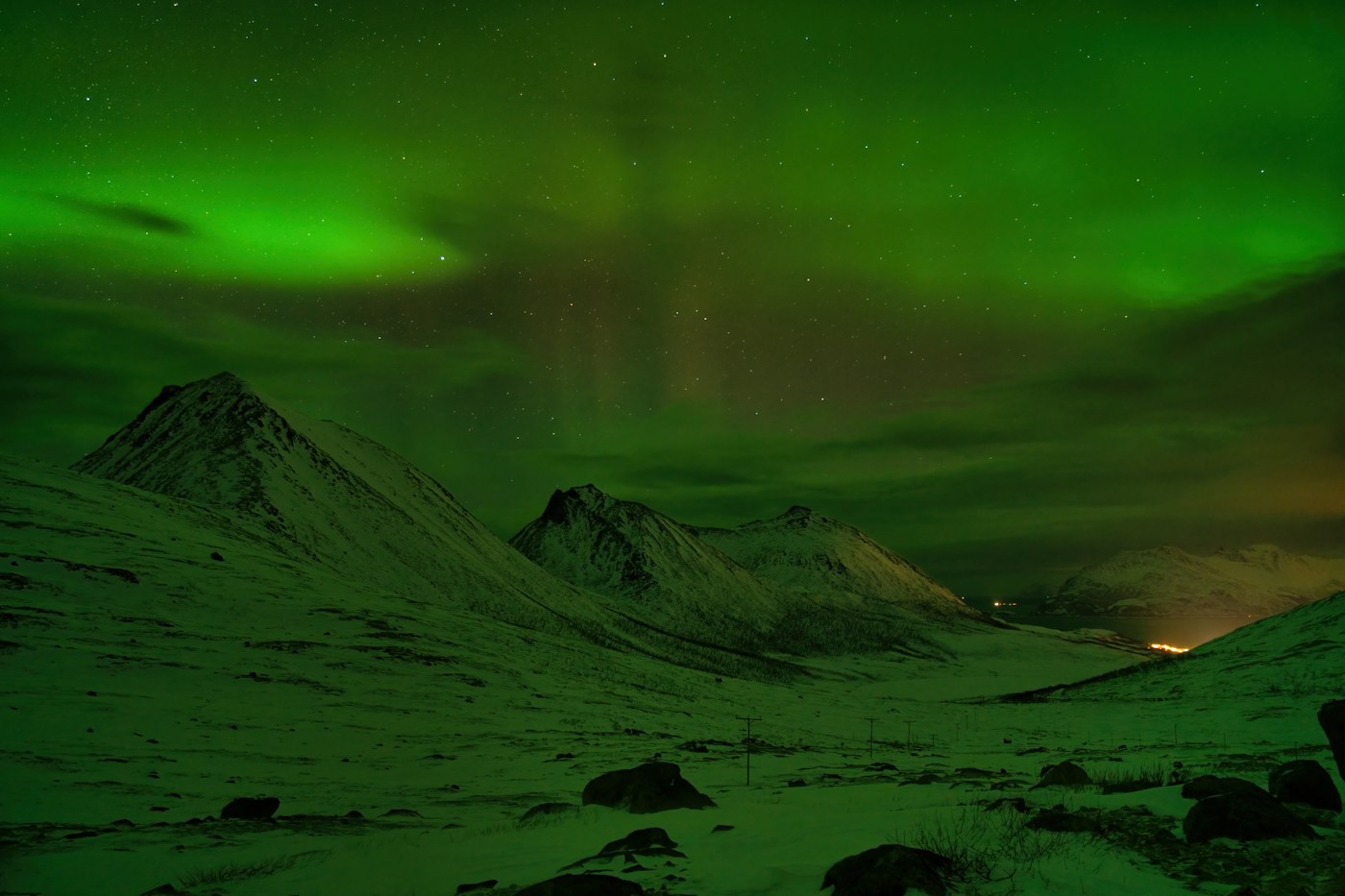 Green northern lights over snowy mountain peaks